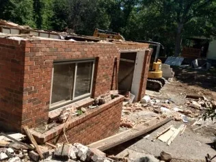 Brick building partly torn down with debris piled in front, demolition