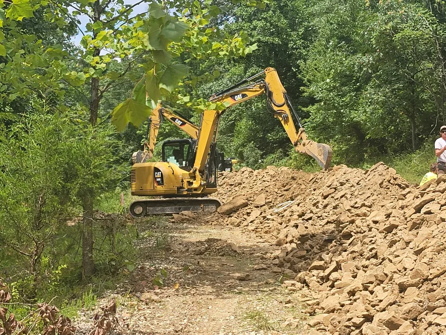 Mini excavator working beside a pile of broken rock, demolition