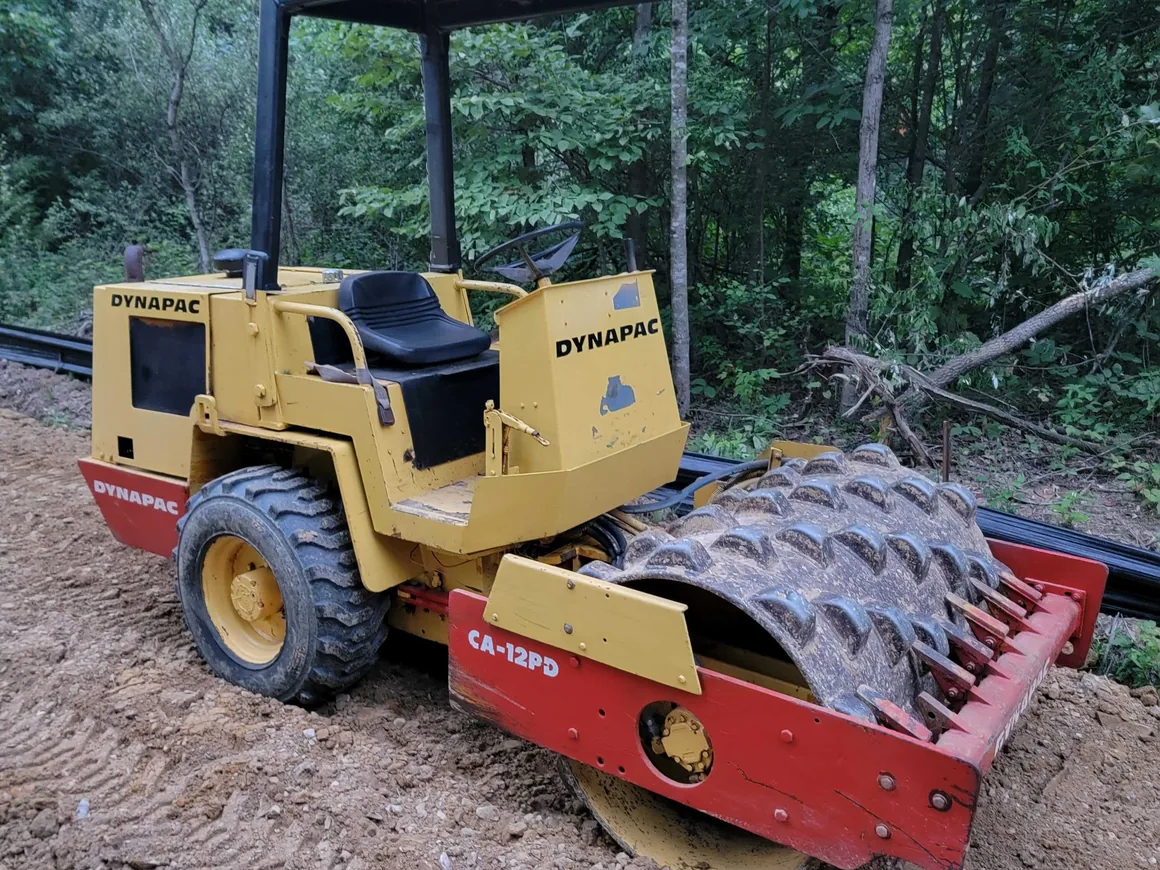 Sheepsfoot compactor roller on a dirt road base, driveway and road building