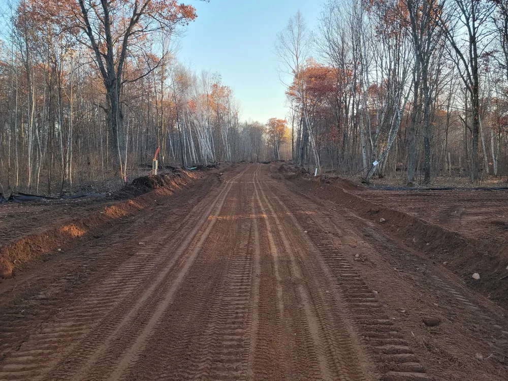 Long graded road through fall woods, driveway and road building
