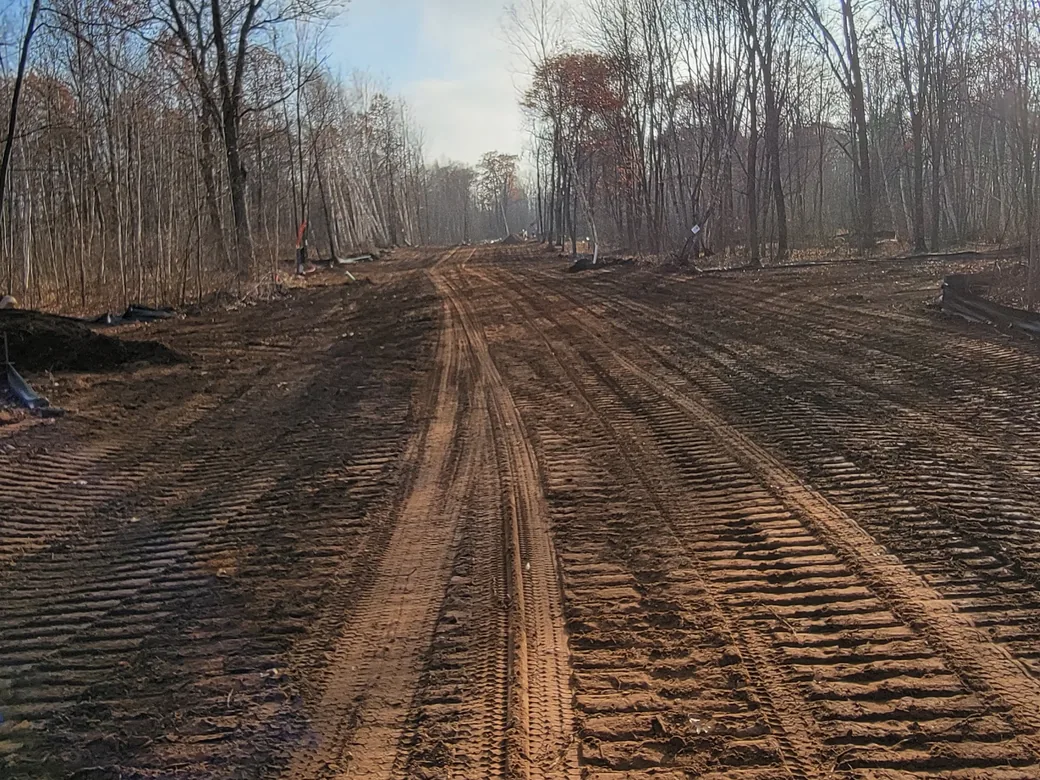 Graded dirt road with track marks through the woods, driveway and road building