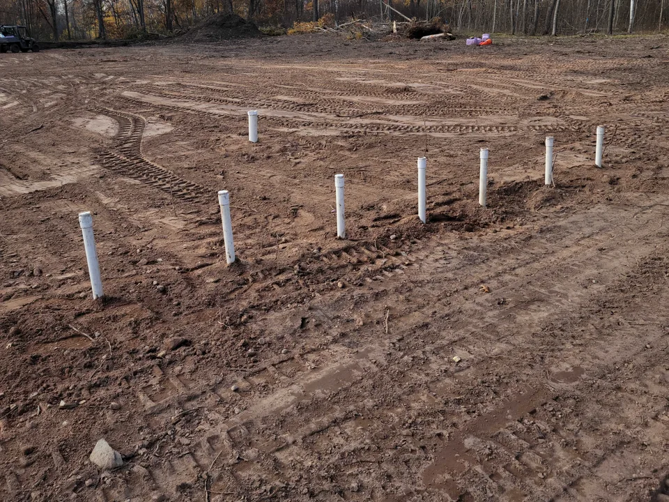 Graded septic drainfield with white inspection pipes, septic system installation