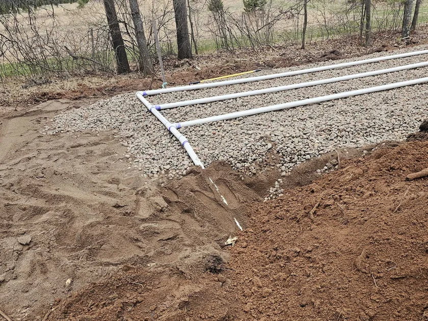 Drainfield distribution pipes laid on a rock bed, septic system installation