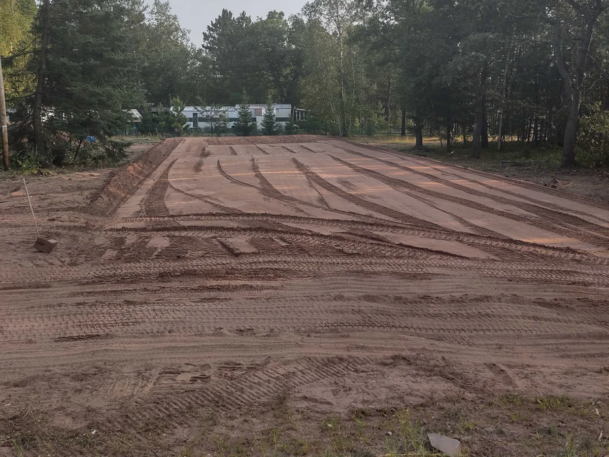 Rough graded lot with fresh track marks at the edge of the trees, site preparation